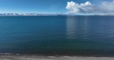 Sakin okyanus suyu bulutları ve gökyüzünü yansıtıyor