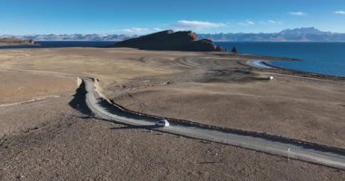 Araba göl kenarındaki dolambaçlı yolda gidiyor.
