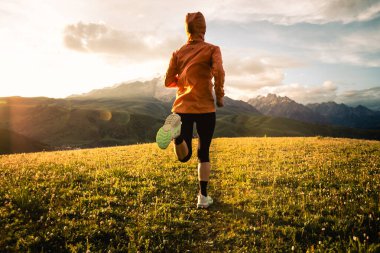 Gün batımında çimen tarlasında koşan kişi