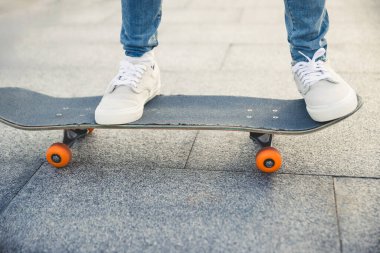 Spor ayakkabılarla kaldırımda dinlenen kaykay