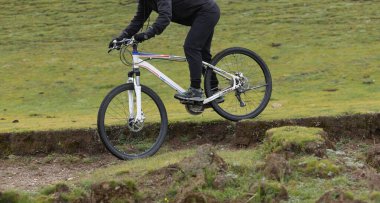 Çimenli arazide bisiklete binen kişi