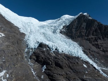 Buzul kayalık dağ manzarasından aşağı akıyor.