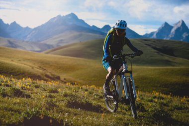 Dağ bisikletçisi çimenli arazide geziyor.