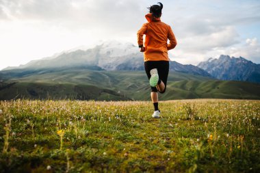 Çimenli tarla dağlarında koşan kişi