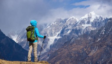 Dağın zirvesinde duran yürüyüşçü manzaraya hayran.
