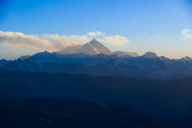 Mavi gökyüzünün altındaki karlı dağ zirveleri