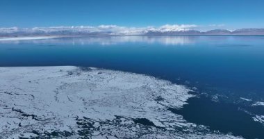 Açık mavi gökyüzünün altında engin buzlu bir manzara.