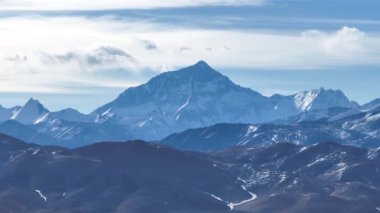 Karlı dağ zirvesi Bulutlu mavi gökyüzünün altında