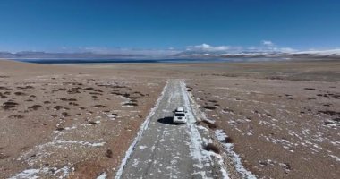 Göl kenarındaki boş yolda giden araba.