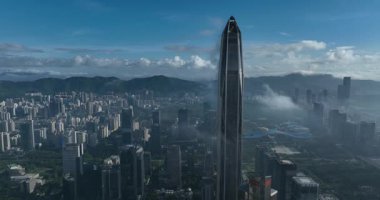 Şehir manzarası ve bulutlarla çevrili uzun gökdelen.