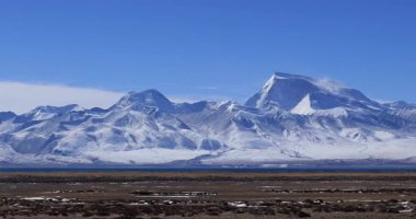 Açık mavi gökyüzünün altında karlı dağlar