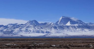 Açık mavi gökyüzünün altında karlı dağlar