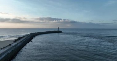 Deniz kenarındaki kırmızı ve beyaz çizgili deniz fenerinin hava görüntüleri.