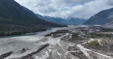 Ormanı ve karla kaplı dağları olan güzel otlakların hava görüntüleri.
