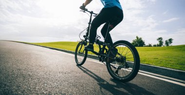 Güneşli yolda katlanan bisiklete binmek