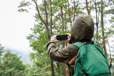 Ormanda cep telefonu kullanan bir kadın.