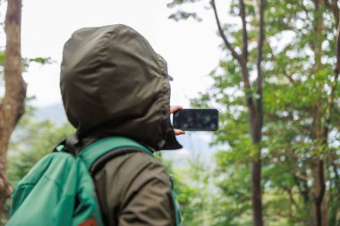 Ormanda cep telefonu kullanan bir kadın.