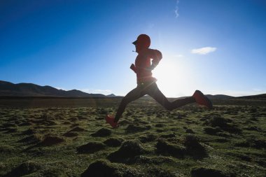 Yüksek rakımlı çayırlarda koşan kadın koşucu.