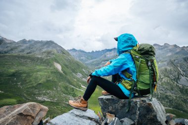Yürüyüş yapan kadın yüksek rakımlı dağın tepesindeki manzaranın tadını çıkarıyor.