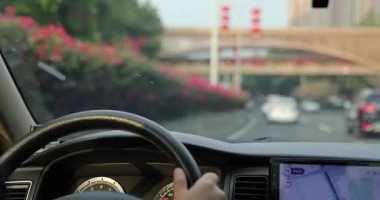 Şehir yolunda araba sürüyorum, eller direksiyonu tutuyor.