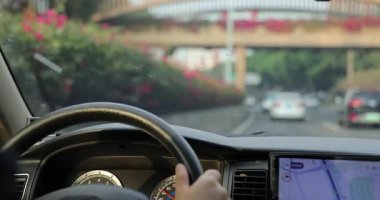 Şehir yolunda araba sürüyorum, eller direksiyonu tutuyor.