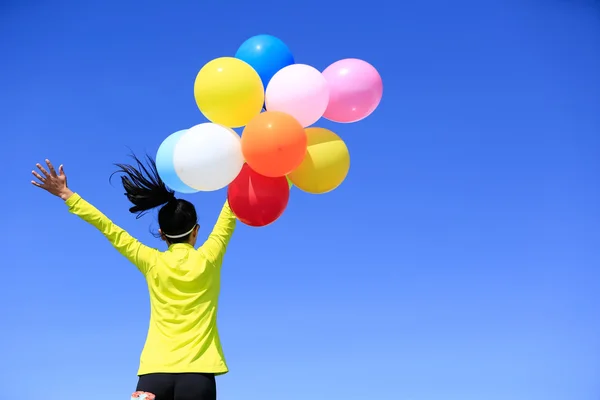 Cheering young woman colorful balloons — Stock Photo, Image