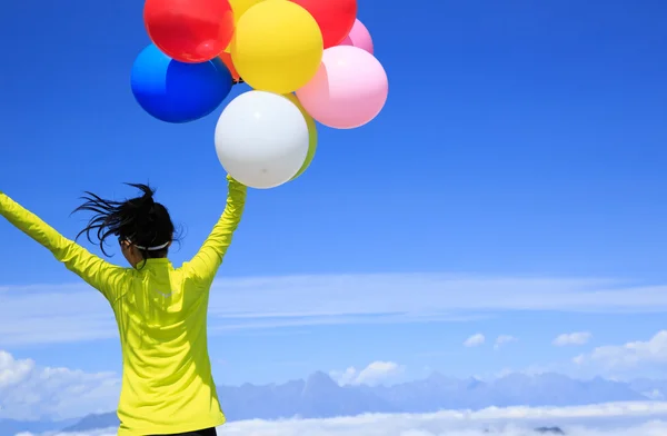 Cheering young woman colorful balloons — Stock Photo, Image