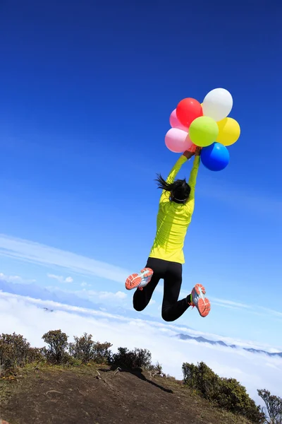 Cheering young woman colorful balloons — Stock Photo, Image