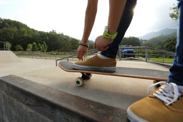 Руки скейтбордиста завязывают шнурки — стоковое фото