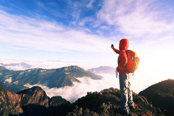 Mulher com smartphone no pico da montanha — Fotografia de Stock