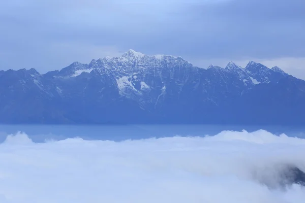 Nuvens e cumes de montanhas nevadas — Fotografia de Stock