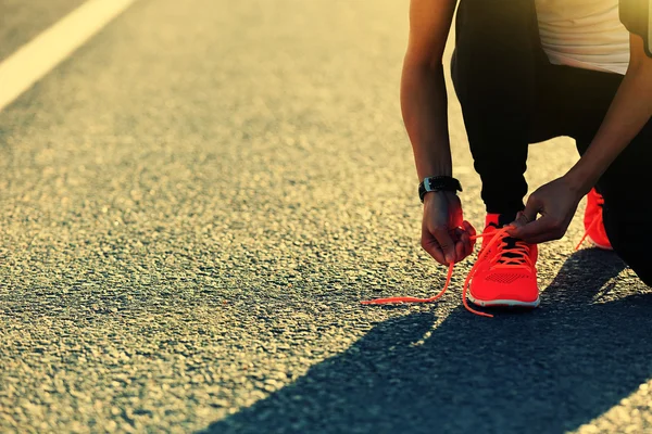 Спортивная женщина завязывающая шнурки — стоковое фото