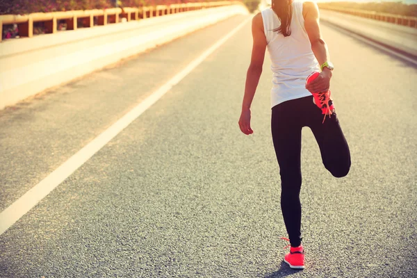Жінка бігунка розтягує ногу — стокове фото