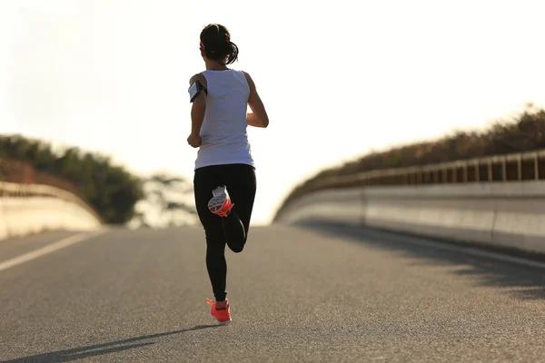 Fitness woman running on sunrise road — Stock Photo, Image