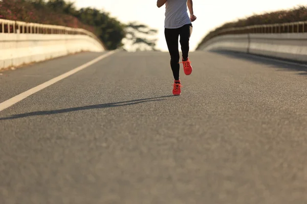 Fitness woman running on sunrise road — Stock Photo, Image