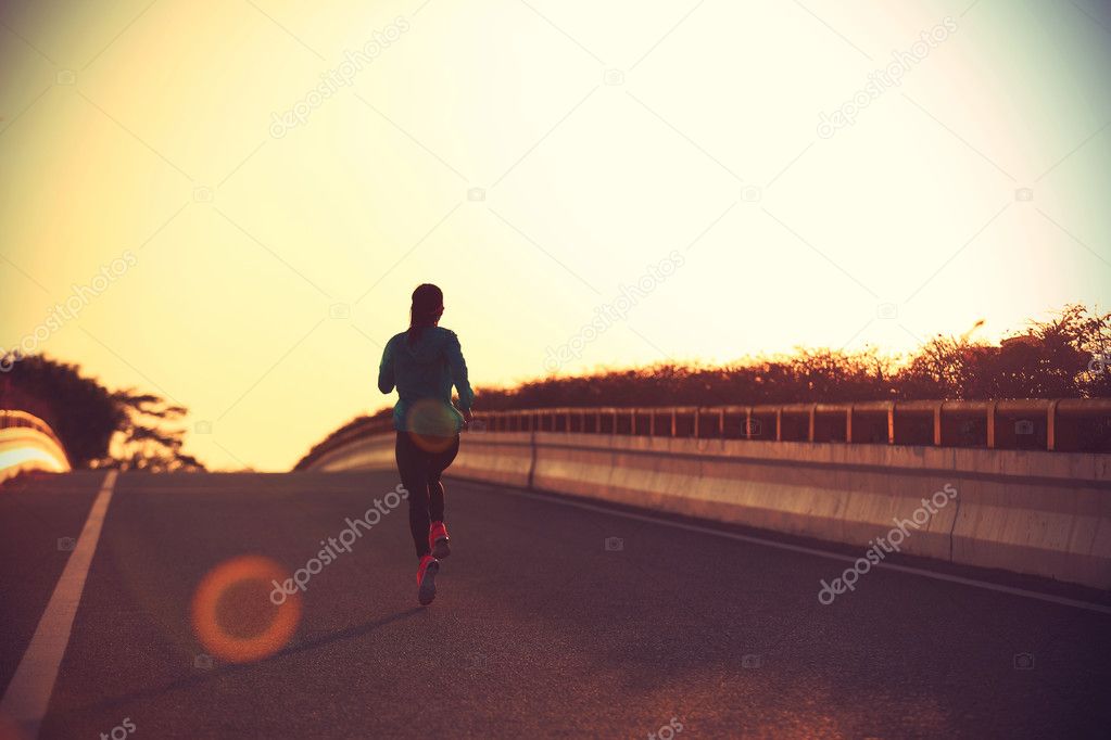 fitness woman running on sunrise road