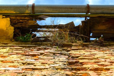 Paslı, mavi gökyüzüne bakan tuğla bir duvarın tepesindeki kötü oluk.