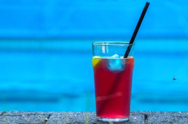 Mavi arka planda, soğuk pembe kuyruklu bir bardağın yakın plan görüntüsü.