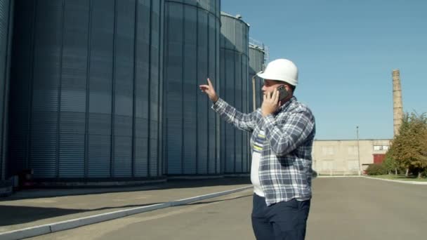 Inżynier rozmawiający przez telefon przy windzie zbożowej — Wideo stockowe