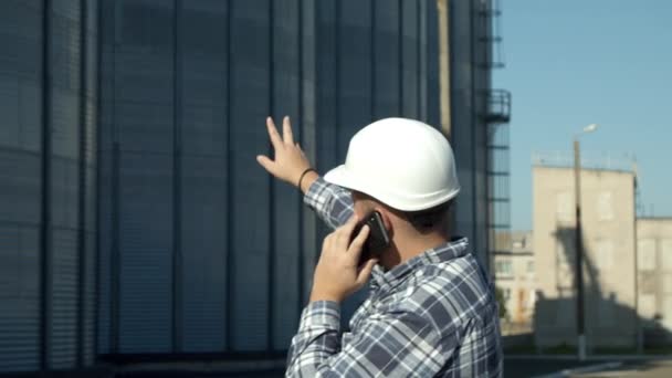 Inżynier rozmawiający przez telefon przy windzie zbożowej — Wideo stockowe