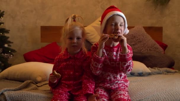 침대에 앉아서 과자를 먹는 아이들을 격려하는 모습 — 비디오
