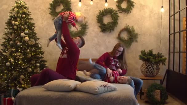 Веселая семья веселится вместе на кровати — стоковое видео