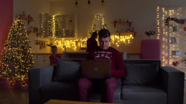 Yılbaşı süslemeleri olan bir adam dizüstü bilgisayarla çalışıyor. — Stok video