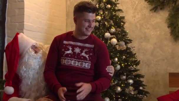 Lächelnder Mann und Weihnachtsmann im gemütlichen Zimmer — Stockvideo
