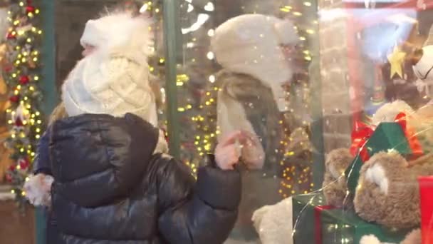 Щасливі діти вивчають іграшки у вікні магазину разом — стокове відео