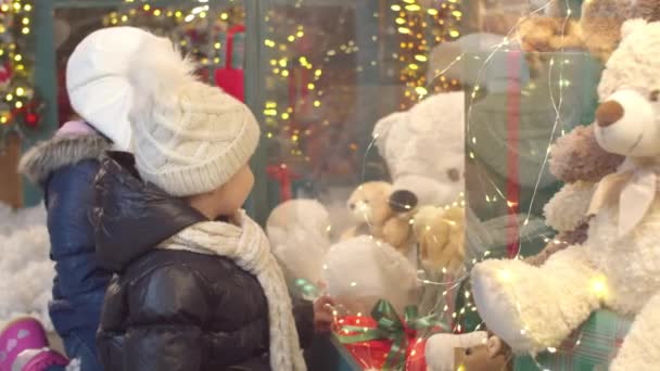 Niños felices examinando juguetes en el escaparate juntos — Vídeos de Stock