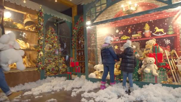 Pareja caminando junto a los niños cerca de la tienda de juguetes y panadería — Vídeos de Stock