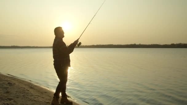 Adult fisherman fishing in morning on lake shore — Stock Video