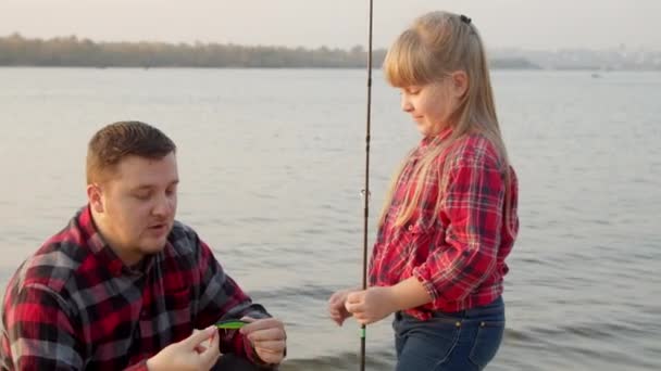 Père montrant poisson appât à fille près du lac — Video