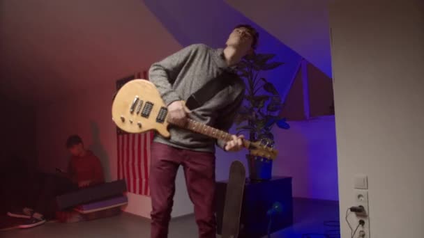 Енергійний молодий чоловік грає рок-музику на гітарі — стокове відео